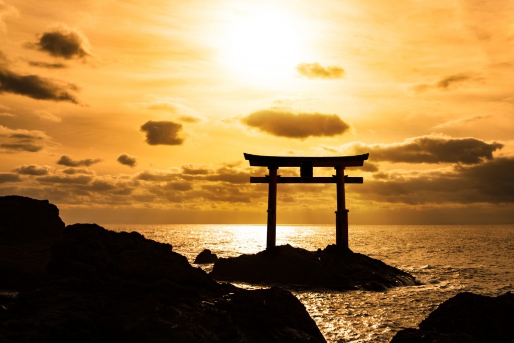 Sunset with the Japanese traditional gate, torii right at the ocean 